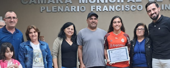 Acompanhada de familiares, Thais Guatimosim recebeu placa das mãos do vereador Lucas Azevedo. (CRÉDITOS: Lucas Rodrigues)